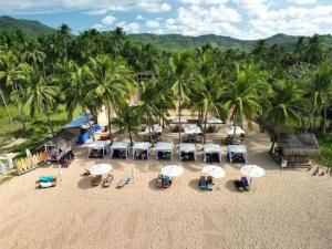 a group of umbrellas on a beach with palm trees at Duli Beach Farm Hostel in Duli