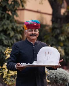 a man holding a plate with a cake on it at Rohet Garh in Rohat +87 photos