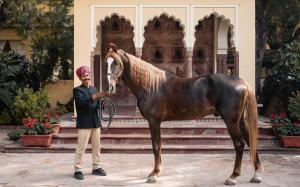 a man standing next to a horse in front of a building at Rohet Garh in Rohat