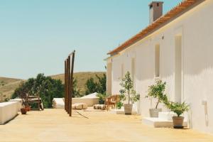 a balcony of a white building with potted plants at Monte da Serra de Baixo By CABRA in Sines