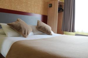 a bed in a hotel room with two pillows on it at Libre Hôtel in La Vespière