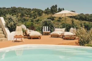 a swimming pool with lounge chairs and an umbrella at Monte da Serra de Baixo By CABRA in Sines