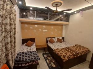 two beds in a room with a ceiling fan at ROOMS vala in Varanasi