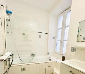 a white bathroom with a shower and a tub at Apparthotel Beauregard 12 cœur de Nantes WIFI in Nantes