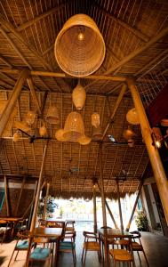 a group of tables and chairs under a straw roof at Hotel Catamaran Bay by Ayur Ayur in Negombo
