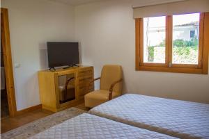 a bedroom with a bed and a tv and a chair at Hotel Rural Casa de Samaioes in Chaves