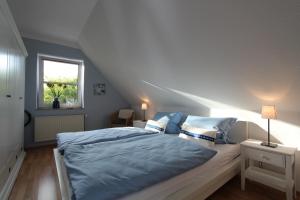 Schlafzimmer mit einem Bett mit blauer Bettwäsche und einem Fenster in der Unterkunft Sea Lounge in Eckernförde