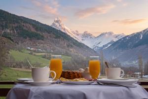 a table with a plate of food and two glasses of orange juice at Becho House in Becho