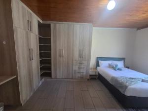 a bedroom with a bed and a cupboard and shelves at The Second Tranquilo in Ermelo