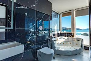 a bathroom with a tub and a toilet and a sink at Hotel Aloha in Sarandë +98 photos