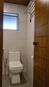 a bathroom with a white toilet and a window at Hotel Arena in Mahe