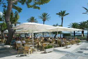 a group of people sitting at tables under umbrellas at Villa Maina by Villa Plus in El Port