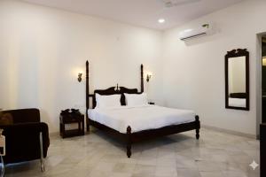 a bedroom with a bed and a chair and a mirror at Achal Bagh - Boutique Stay Abu Road in Māwāl
