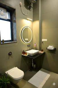 a bathroom with a toilet and a sink and a mirror at Achal Bagh - Boutique Stay Abu Road in Māwāl