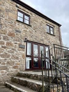 a stone building with a window and stairs at Saddle Cottage in Penzance