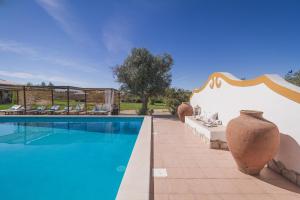 a villa with a swimming pool and vases on a patio at Monte Chalaça - Turismo Rural in Ferreira do Alentejo