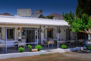 a white building with tables and chairs in front of it at Giasemi Rooms in Livadi Astypalaias