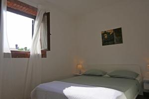 a white bedroom with a bed and a window at Apartment Terrarossa 2 in Fažana