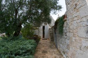 an alleyway leading to a building with a stone wall at B&B La Gufa in Cisternino