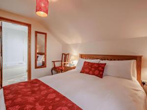 a bedroom with a white bed with a red pillow at 3 Bed in Bideford oc-05171 in Woolfardisworthy
