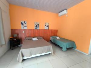 two beds in a room with an orange wall at Asas da Maré Pousada in Bragança