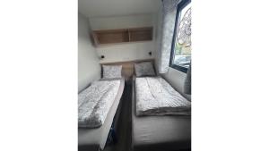 two beds in a small room with a window at Camping in de Bongerd - Kust&Q in Oostkapelle