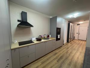 a kitchen with white cabinets and a wooden floor at Ianmamaia in Mamaia