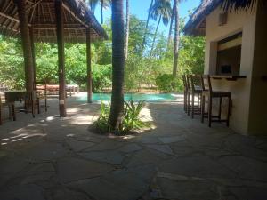 a patio with chairs and a table and a pool at Marlin room in Watamu