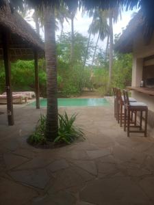 a patio with chairs and a tree and a pool at Marlin room in Watamu