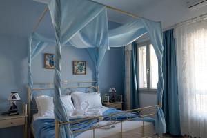 a bedroom with a canopy bed with blue walls at Giasemi Rooms in Livadi Astypalaias