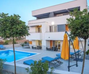 a villa with a swimming pool and a house at Apartments & Rooms Villa Casia in Novalja