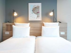 two beds in a room with white pillows at AppartHotel Mercure Paris Boulogne in Boulogne-Billancourt