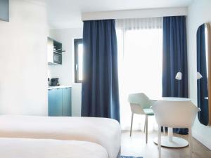 a hotel room with a bed and a table and chairs at AppartHotel Mercure Paris Boulogne in Boulogne-Billancourt