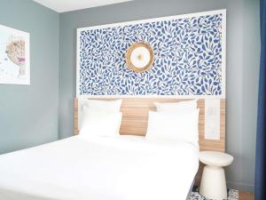 a bedroom with a white bed and a blue wall at AppartHotel Mercure Paris Boulogne in Boulogne-Billancourt +77 photos