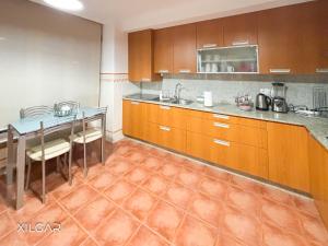 a kitchen with wooden cabinets and a table with chairs at Xilgar - Chalet Ensenada de Lanzada in Sanxenxo