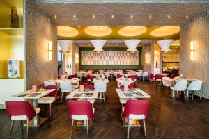 a restaurant with white tables and red chairs at Barceló Malaga in Málaga