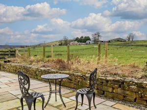 two chairs and a table in front of a stone wall at 3 Bed in Brampton oc-89994 in Slaggyford