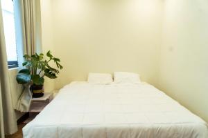 a white bed in a room with a plant at My Sweet House in Hòa Bình