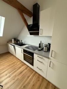 a white kitchen with a sink and a stove at ღLIBORIA I Loft am Riegsee in Aidling +4 photos