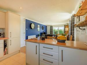 a kitchen with white cabinets and a blue wall at 3 Bed in Braunton oc-87699 in Braunton