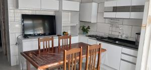 a kitchen with a table with chairs and a television at Casa reformada com Wi-Fi, garagem e lavanderia in Capão da Canoa