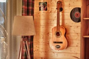 a guitar hanging on a wall next to a lamp at Domek Sol Wilcza Zagroda in Kudowa-Zdrój