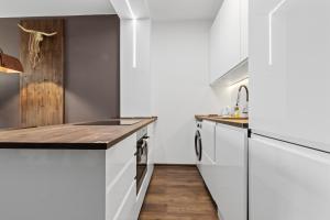 a kitchen with white cabinets and a wooden floor at LAM Western AC in Bratislava