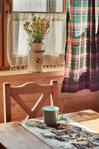 a table with a cup and a chair and a window at Domek Sol Wilcza Zagroda in Kudowa-Zdrój