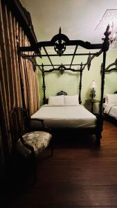 a bedroom with an antique bed and a chair at Casa Pichay in Vigan