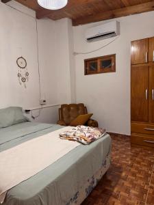 a bedroom with a bed with a chair and a cabinet at Raíces Vivas Selva Misionera in Oberá