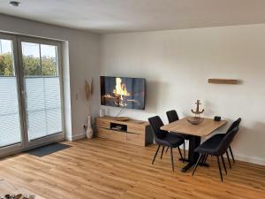 a dining room with a table and a tv on the wall at Ferienwohnung Meeresleuchten - Glowe in Glowe