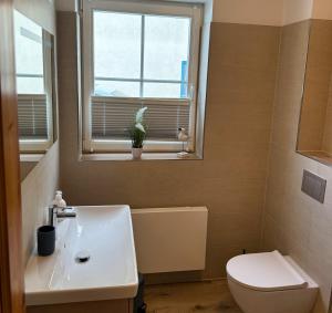 a bathroom with a toilet and a sink and a window at Ferienwohnung Meeresleuchten - Glowe in Glowe +11 photos