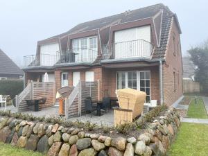 a brick house with a patio with a table and chairs at Amselkoje in Süderende