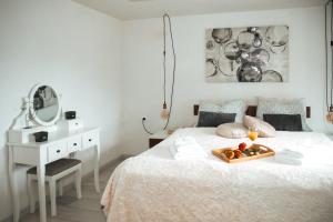 a white bedroom with a tray of fruit on a bed at Apartman Incerum in Požega